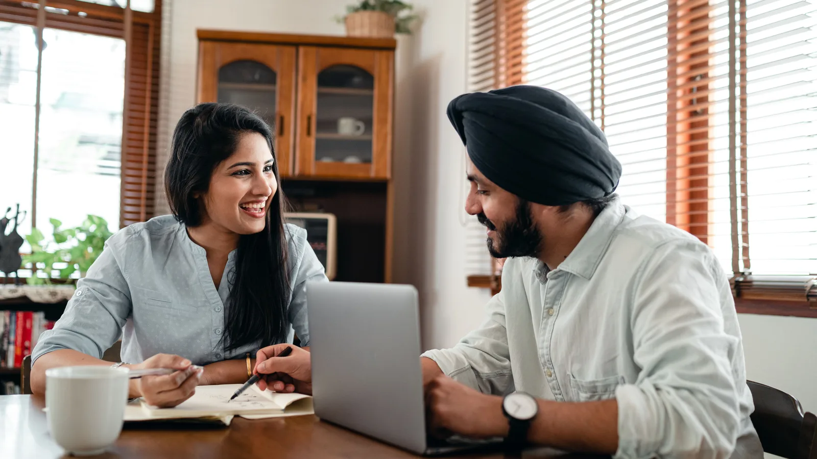 Founders at a shared desk in an Indian workspace, documents open between them